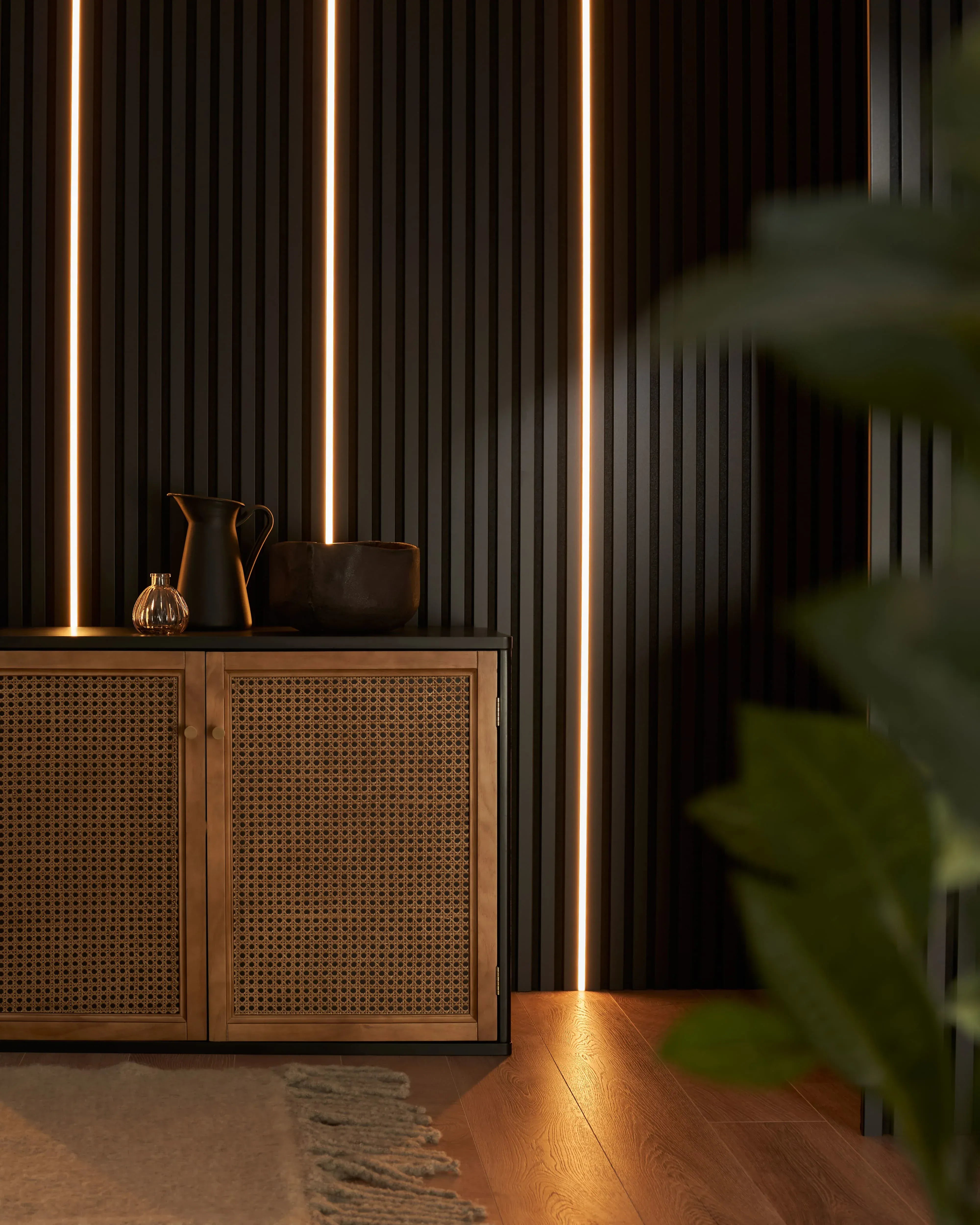 Wooden cabinet with woven design against a dark slat feature wall with vertical light strips